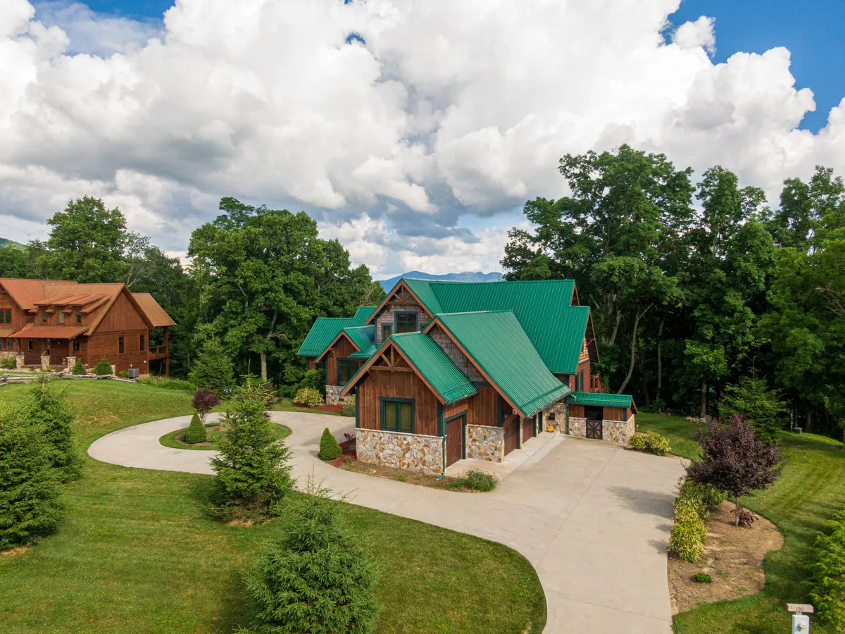 A rustic wooden structure with a green metal roof stands amid landscaped gardens. The inviting porch and surrounding greenery offer a serene backdrop for outdoor relaxation, barbecues, and sunset views—spaces where both people and pets can unwind after a day of adventure.