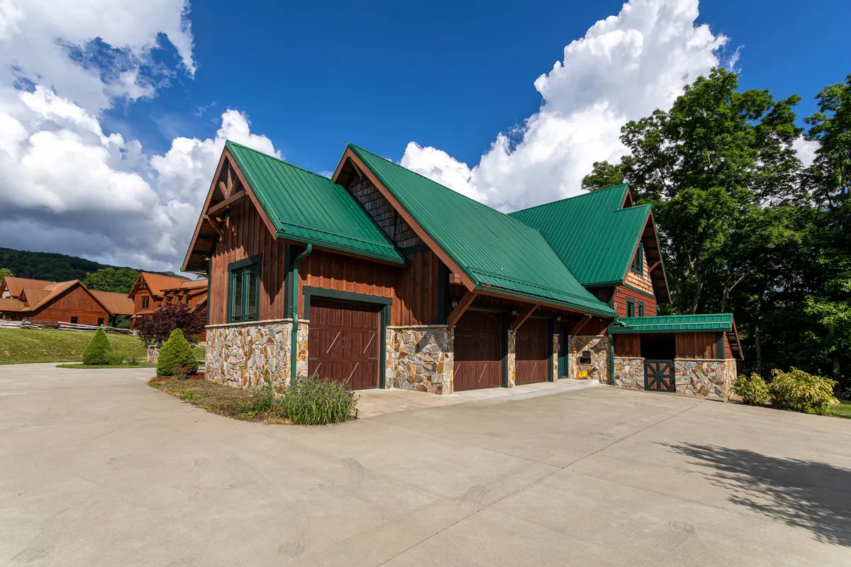 This image shows the exterior of White Eagle Lodge, featuring a charming wooden structure with a green metal roof and a stone façade. The house is surrounded by a landscaped garden and hints at open outdoor spaces ideal for pets and family gatherings. The scene radiates a rustic and inviting atmosphere, making it easy to imagine guests arriving with their pets.